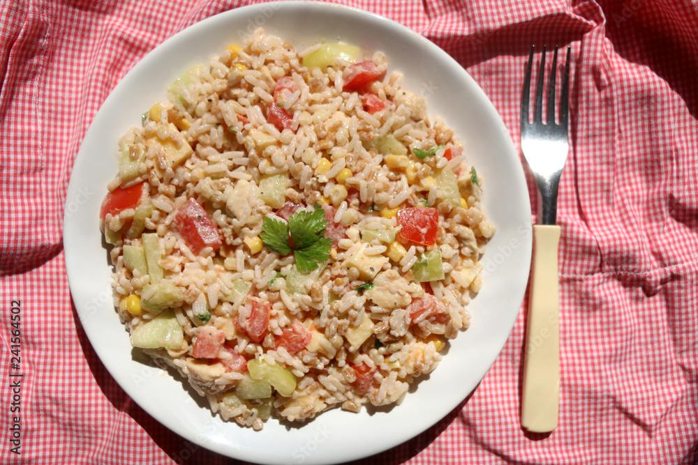 Cold salad with chicken, rice, various vegetables (tomato, pepper, cucumber, corn) and seasoning. Decorated with parsley leaves. Top view. Cold salad with chicken, rice, various vegetables (tomato, pepper, cucumber, corn) and seasoning. Decorated with parsley leaves. Top view.
