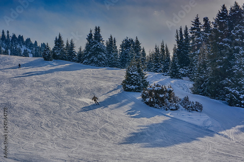 Winter landscape with snow, forest and skiers in Karakol, Kyrgyzstan.