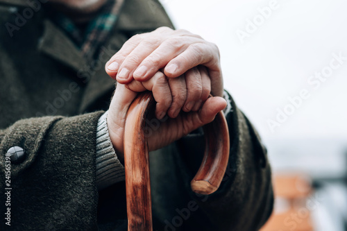 Upset mature male holding walking stick in both hands