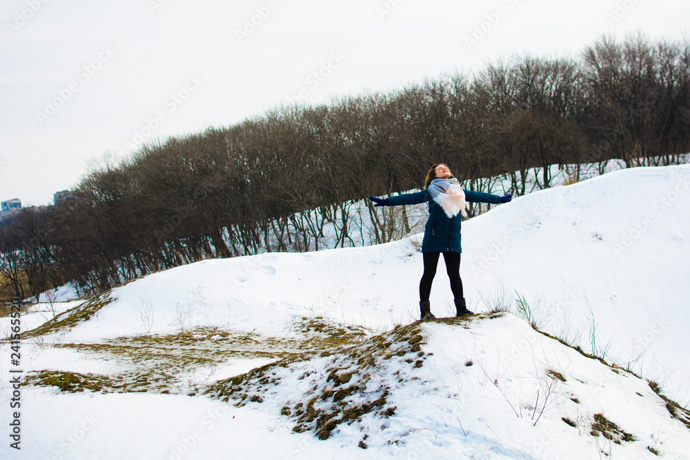 girl in winter stands on a hill with his hands up. concept of freedom or victory