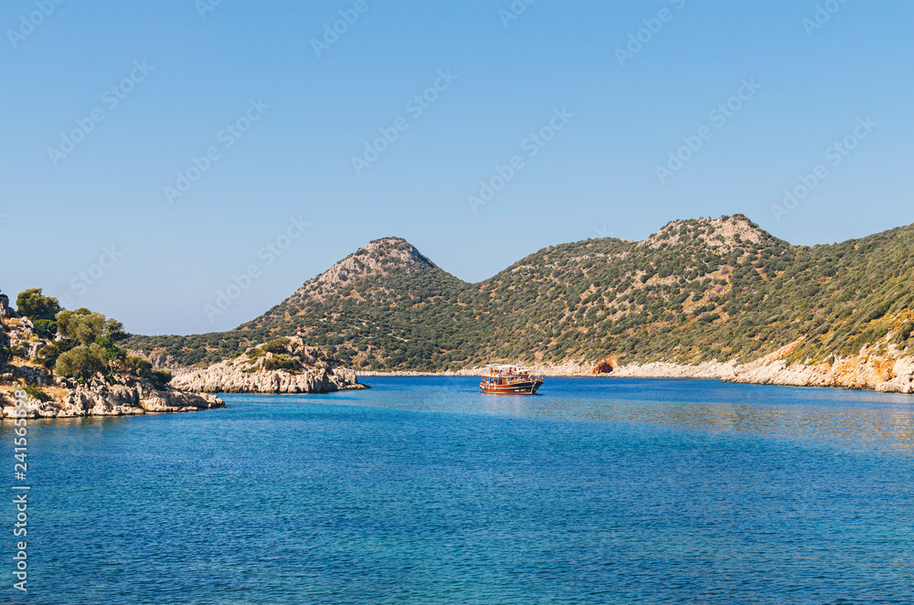 Panorama view of Tourist cruise near small rocky island in Ufakdere, Kas, Antalya, Mediterranean coast of Turkey