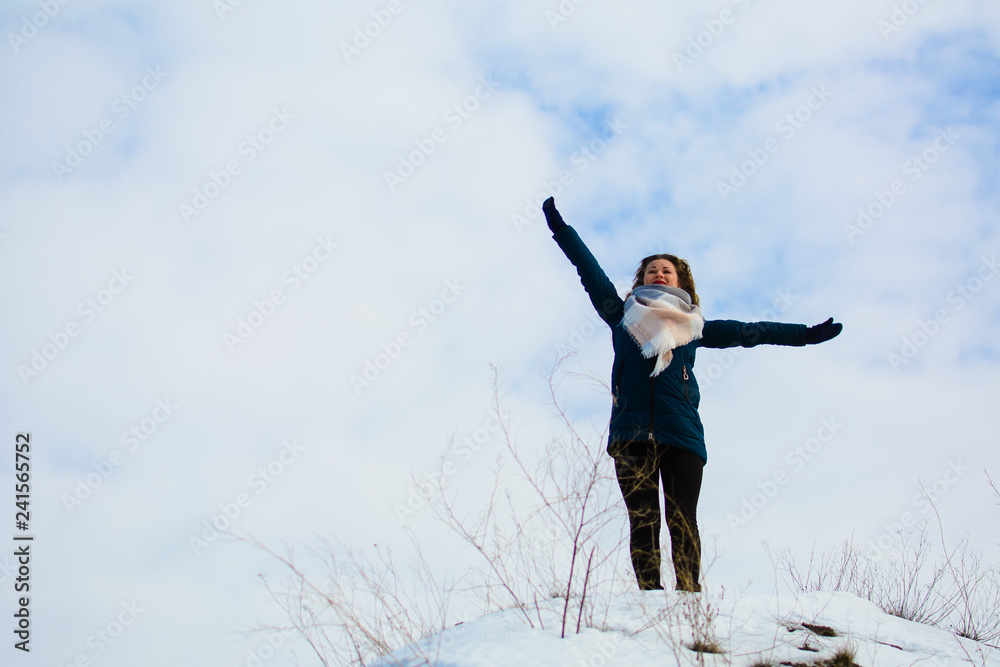 girl in winter stands on a hill with his hands up. concept of freedom or victory girl in winter stands on a hill with his hands up. concept of freedom or victory