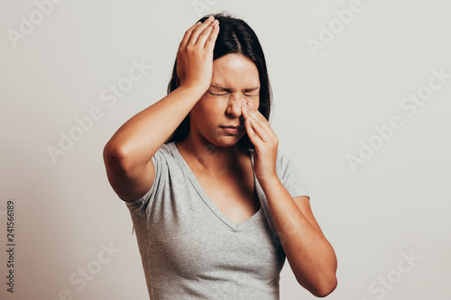 Sinus pain, sinus pressure, sinusitis. Sad woman holding her nose and head because sinus pain