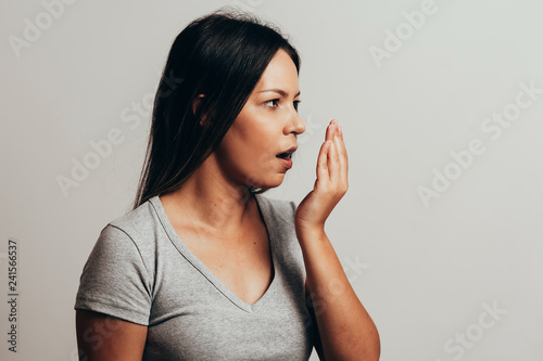Bad breath. Halitosis concept. Young woman checking his breath with his hand. photo