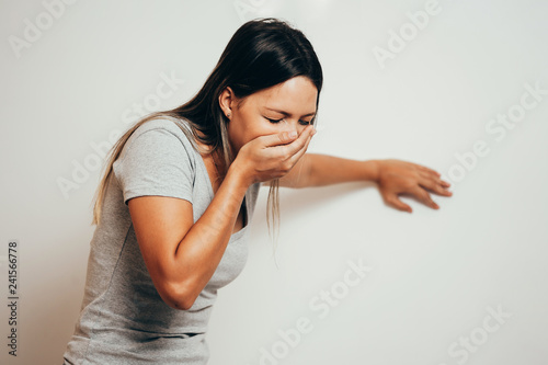 Portrait of young woman drunk or sick vomiting over gray background photo