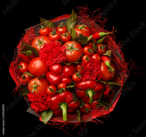 Unique gift handmade in the form of a bouquet consisting of a tomatoes, red peppers, bay leaves on a black background. Top view