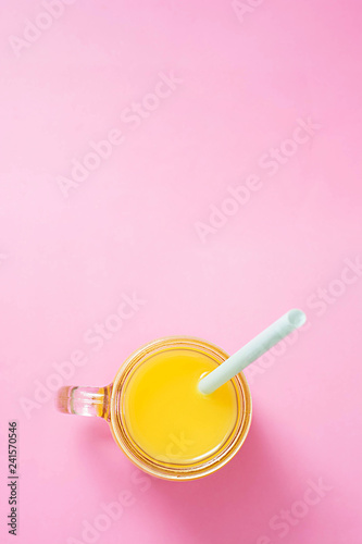 Colorful composition with mason jar glass full of fresh orange juice with straw, fruit, isolated on pink background. Close up, copy space, top view.