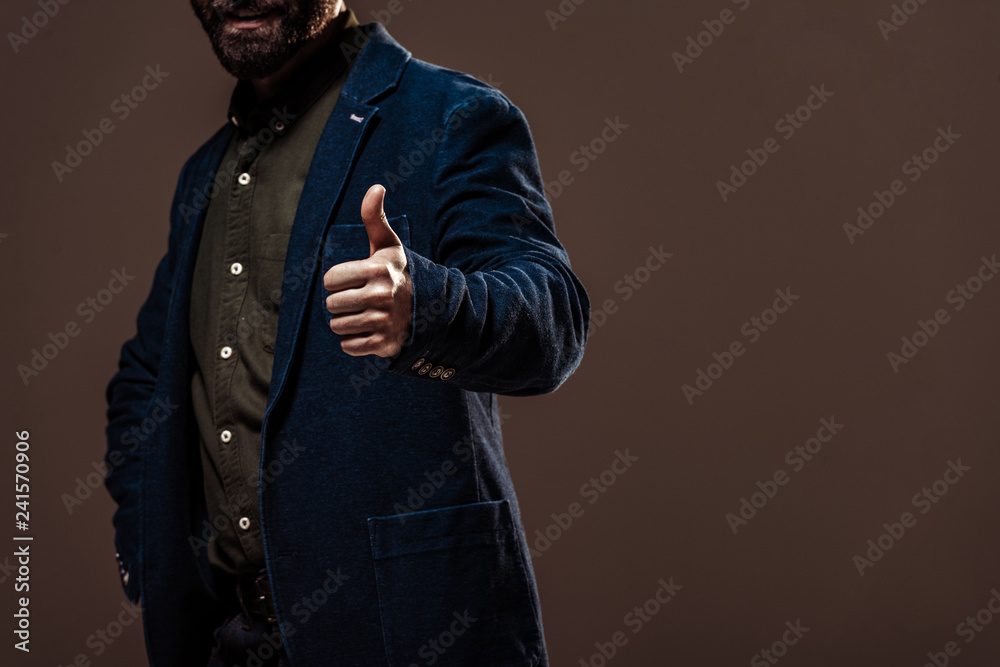cropped view of man showing thumb up isolated on brown cropped view of man showing thumb up isolated on brown