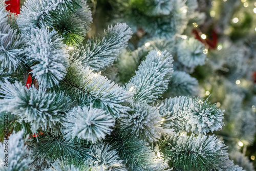 Closeup decorated christmas branch with snow. Led light and other ornaments hang on christmas branch tree with colorful light bokeh background. Merry christmas and happy new year concept.