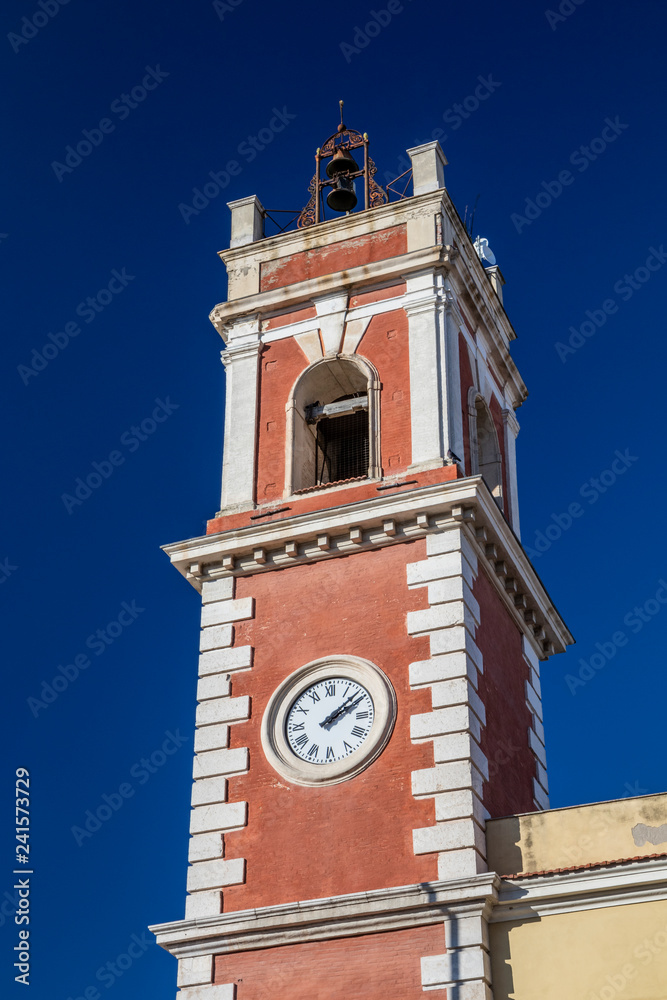 Clock tower, red with white bricks. The building dates back to the nineteenth century. Bells on the top. Cerignola, Puglia, Italy.