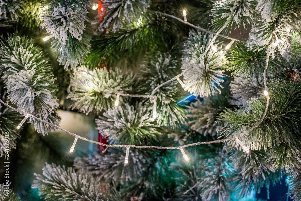 Closeup decorated christmas branch with snow. Led light and other ornaments hang on christmas branch tree with colorful light bokeh background. Merry christmas and happy new year concept.