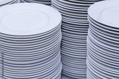 large stacks of clean white plates after washing in the kitchen