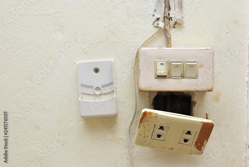 a light switch and electrical socket switch with damaged wiring on the wall