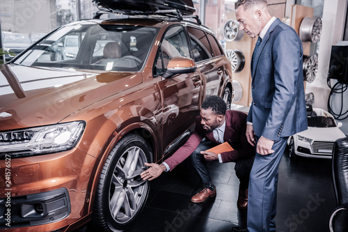 Sales manager of car salon telling his client about the wheels © Viacheslav Yakobchuk