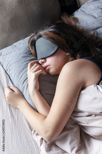The girl in a sleep mask is resting in her bed. Beautiful tinted photo.