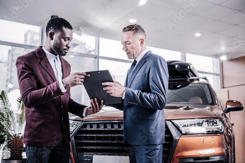 Fototapeta Naklejka Na Ścianę i Meble -  Businessman signing contract while buying new brown hatchback car