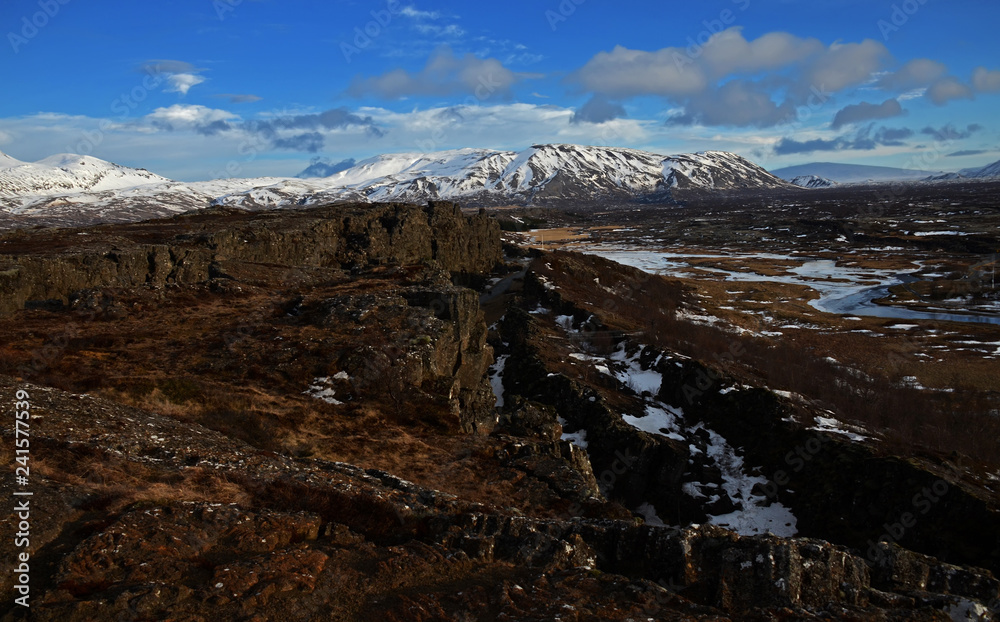 Typical Icelandic landscape: Thingvellir National Park, rivers, lava fields covered with snow against the backdrop of mountains and sky