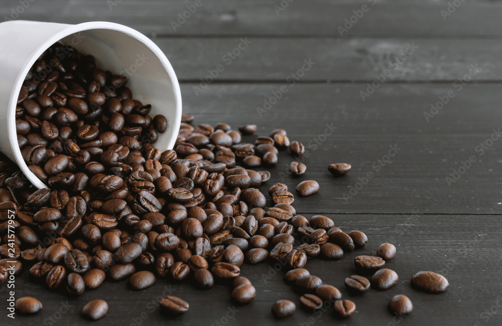 white paper cup and coffee beans on old wooden with soft-focus and over light in the background white paper cup and coffee beans on old wooden with soft-focus and over light in the background