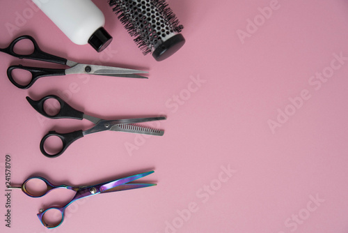 Professional hair dresser tools on pink background with copy space. Hair stylist equipment set. Scissors, brush, hairbrush, balm flat lay top view.