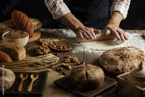 Male hands roll out dough on kitchen floured surface background with cooking background, close up. Cooking process concept.