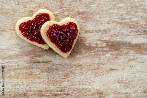  2 heart-shaped sandwich bread in a corner, with strawberry jam on a cozy wooden background, love concept, for Valentine's Day, Mother's Day, Father's Day, Christmas, holidays.