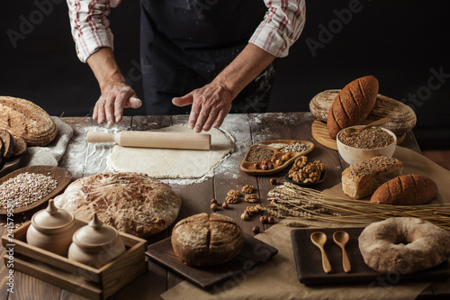Different kinds of fresh bread, focaccia, typical Italian bread with crispy and very tasty crust and male hands rolling out dough for Italian pizza. Healthy eating and traditional bakery concept.