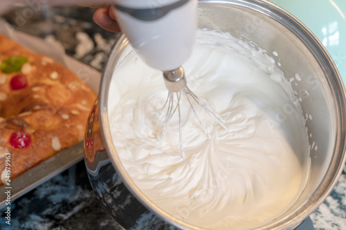 Person beating the cream in a bowl to fill the king's cake.