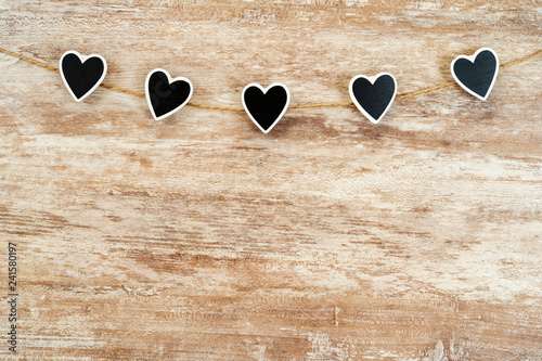 Cozy wooden background, with 5 black hearts fastened between them with a hemp rope, love concept, for Valentine's Day, Mother's Day, Father's Day, Christmas, holidays.
