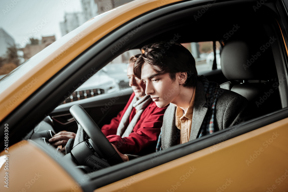 Handsome dark-haired youngster feeling excited choosing new car