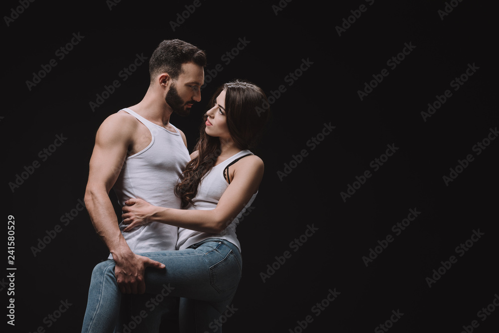 handsome man hugging woman in white singlet isolated on black