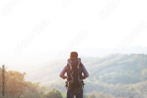 young man hiking traveling standing on top of cliff in summer travel Lifestyle wanderlust adventure with backpack enjoying on peak mountain. Tourist traveler on background valley landscape view. 