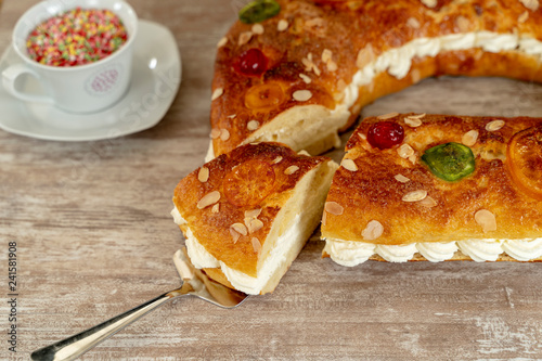 King's cake made by hand in the oven, on a cozy wooden base, and a cup with colorful chocolate stars.