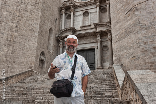A middle aged man is a tourist on the steps of the Cathedral