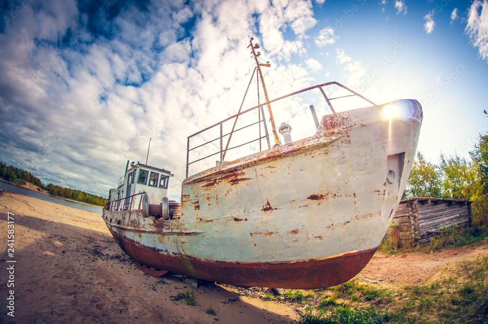 abandoned boat on the sandy shore of a lake on a sunny day. distortion perspective fisheye lens abandoned boat on the sandy shore of a lake on a sunny day. distortion perspective fisheye lens