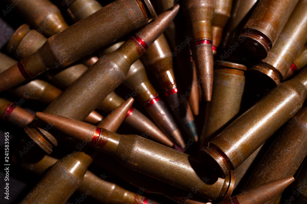 A lot of rifle ammo. AK-47 bullet cartridge. Armor piercing cartridge close up view. Underexposed photo.