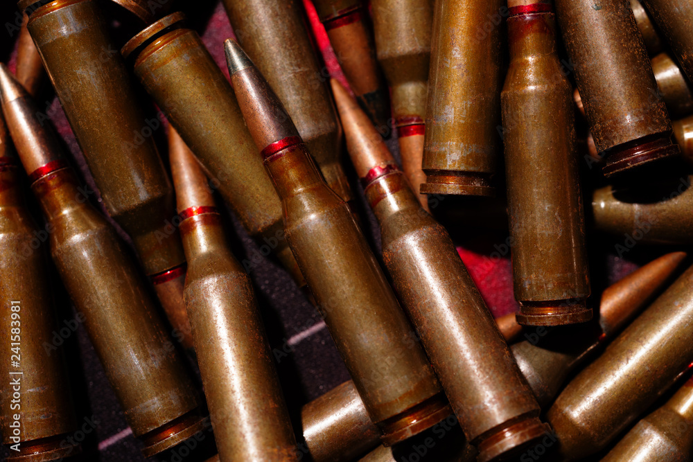 A lot of rifle ammo. AK-47 bullet cartridge. Armor piercing cartridge close up view. Underexposed photo. A lot of rifle ammo. AK-47 bullet cartridge. Armor piercing cartridge close up view. Underexposed photo.