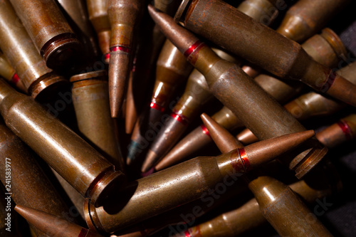 A lot of rifle ammo. AK-47 bullet cartridge. Armor piercing cartridge close up view. Underexposed photo.