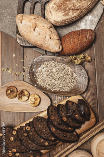 Whole grain, whole loaf and sliced pieces of multigrain bread contains whole grains ( poppy, millet, flaxseed, pumpkin seeds, and sunflower seeds) isolated on dark wooden table . © alfa27