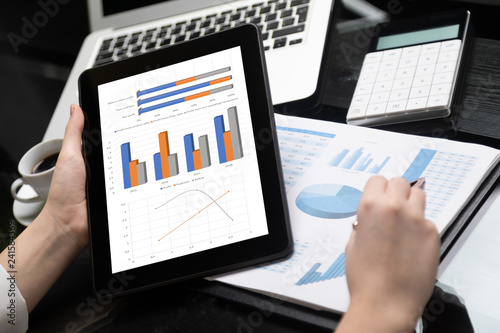 Close-up of hand holding tablet and point pen at chart