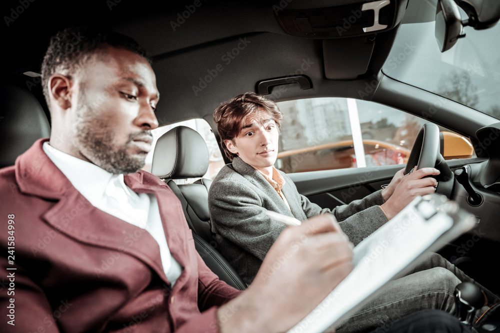 Bearded driving instructor putting marks after test driving Bearded driving instructor putting marks after test driving