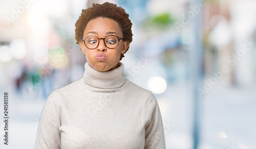 Young beautiful african american woman wearing glasses over isolated background puffing cheeks with funny face. Mouth inflated with air, crazy expression.