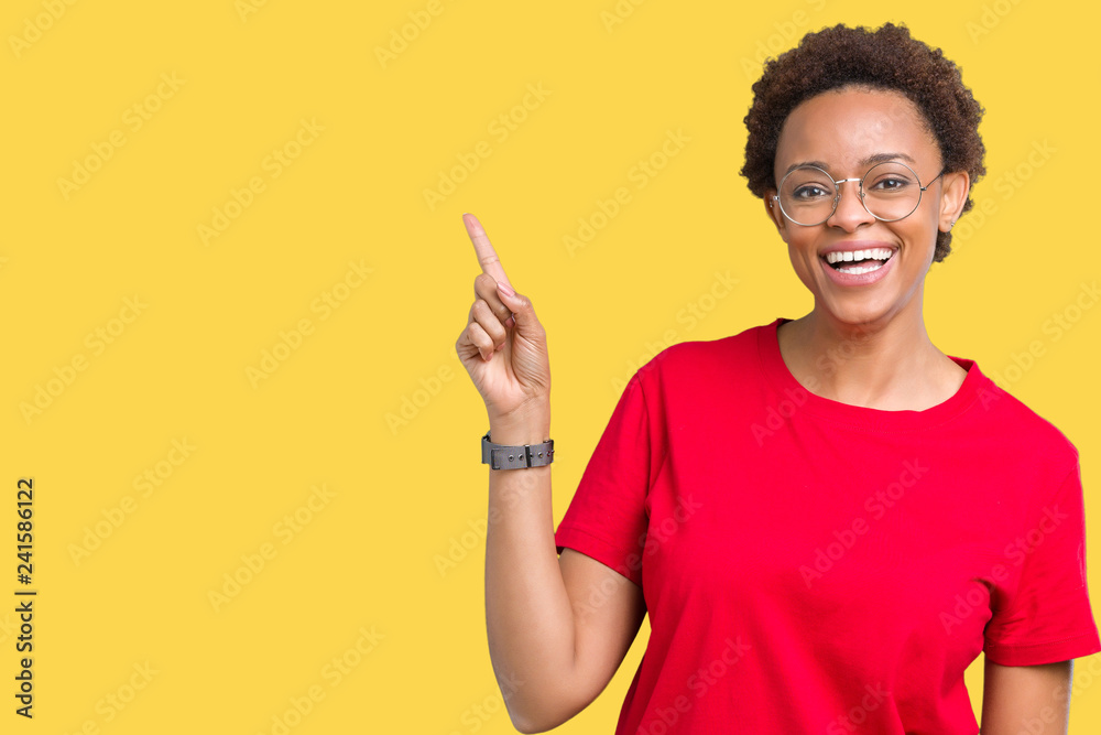 Beautiful young african american woman wearing glasses over isolated background with a big smile on face, pointing with hand and finger to the side looking at the camera.