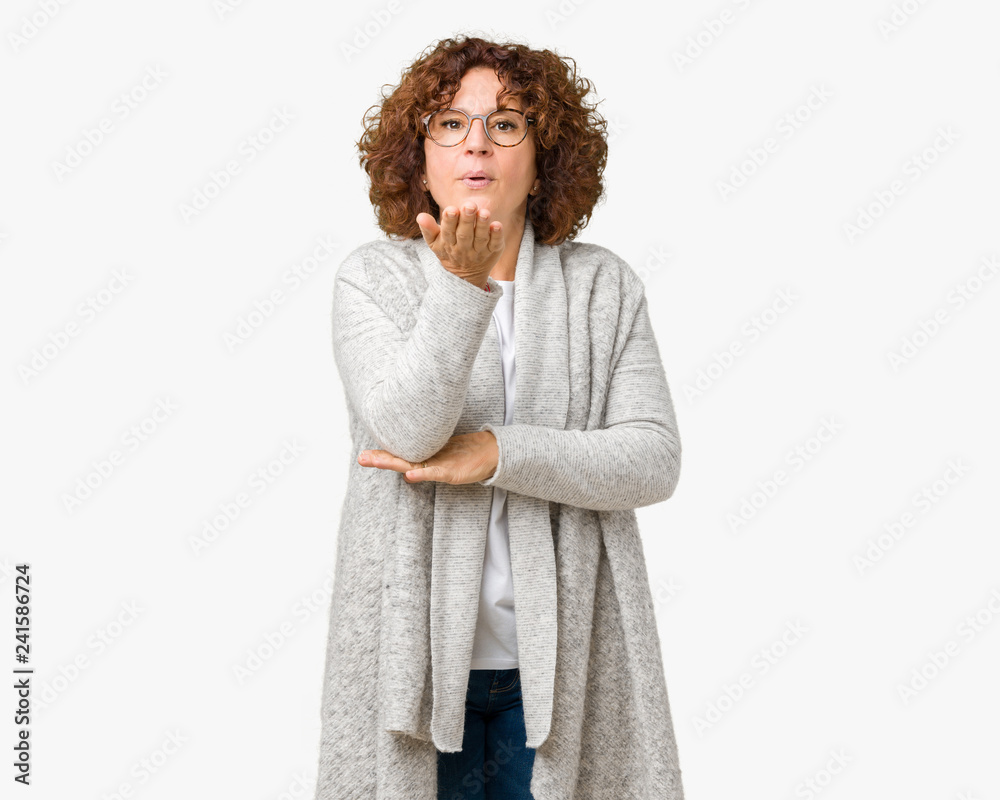 Beautiful middle ager senior woman wearing jacket and glasses over isolated background looking at the camera blowing a kiss with hand on air being lovely and sexy. Love expression. Beautiful middle ager senior woman wearing jacket and glasses over isolated background looking at the camera blowing a kiss with hand on air being lovely and sexy. Love expression.