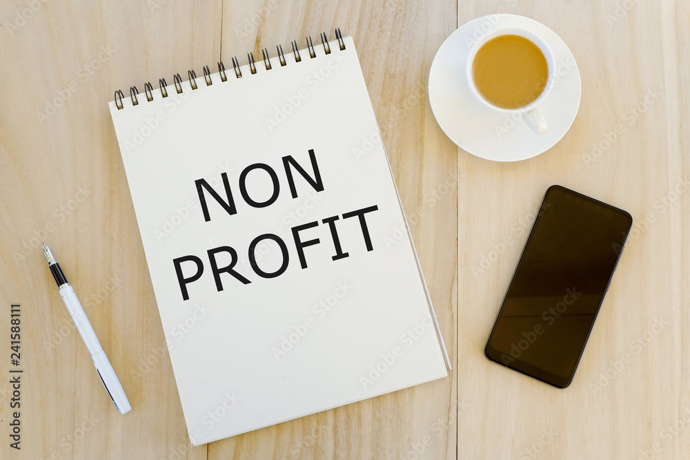 Top view of a cup of coffee,mobile phone,pen and notebook written with Non Profit, Business and finance concept. Top view of a cup of coffee,mobile phone,pen and notebook written with Non Profit, Business and finance concept.