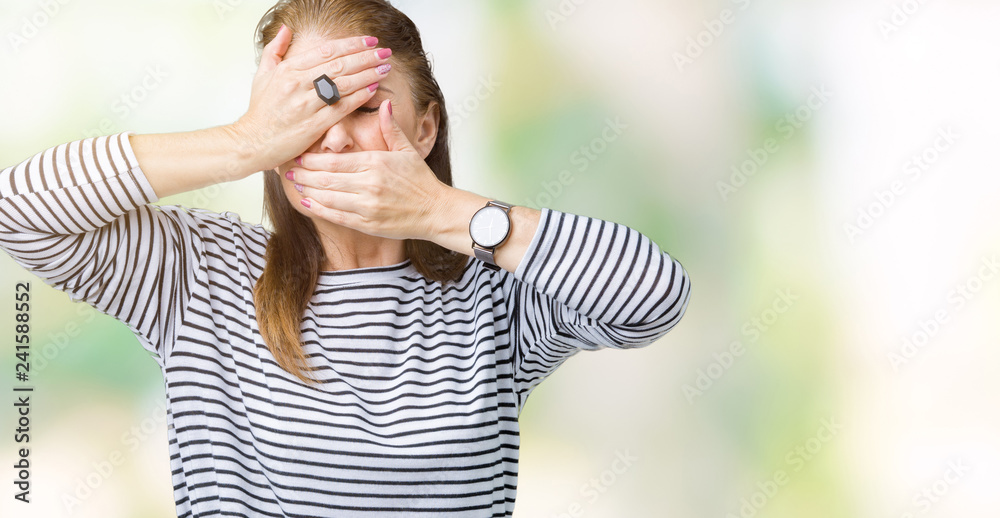 Fototapeta premium Middle age mature beautiful woman wearing stripes winter sweater over isolated background Covering eyes and mouth with hands, surprised and shocked. Hiding emotion