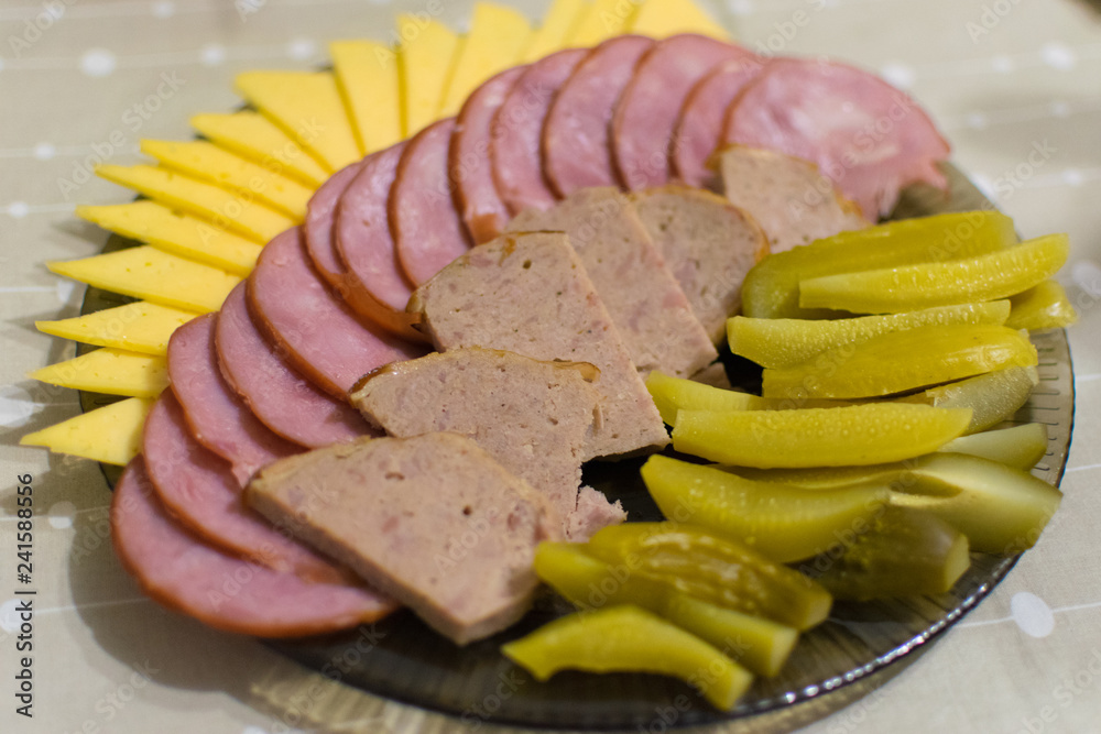 Sausage sliced and laid on a plate, cucumbers, cheese.