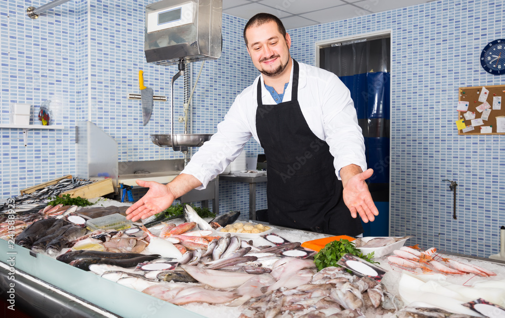 Adult man in black apron standing near fish counter