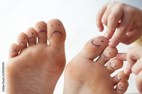 Female toes with painted smileys and children s hands. Foot care concept  pedicure.