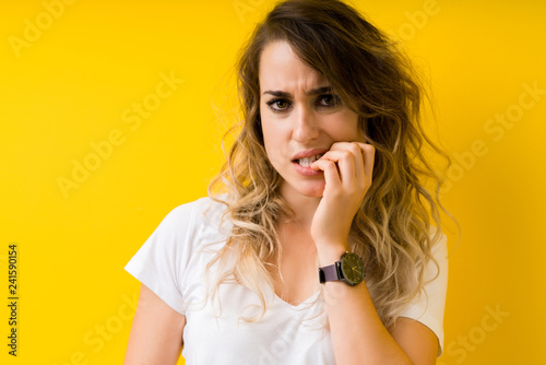 Young beautiful blonde woman over yellow background looking stressed and nervous with hands on mouth biting nails. Anxiety problem. © Krakenimages.com