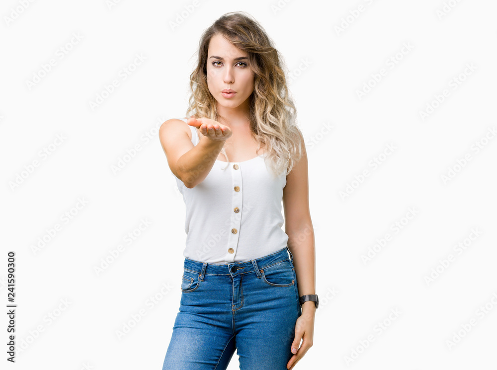 Young beautiful blonde woman over isolated background looking at the camera blowing a kiss with hand on air being lovely and sexy. Love expression. Young beautiful blonde woman over isolated background looking at the camera blowing a kiss with hand on air being lovely and sexy. Love expression.